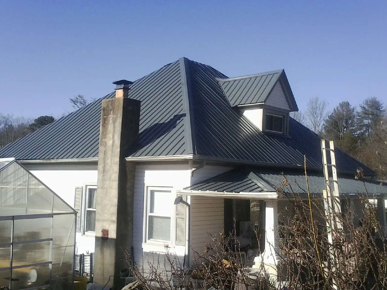 Dark blue standing seam metal roof on a white farmhouse with dormer — Slate & Tile Roof Repair by Roofing Brothers in Yarmouth Port