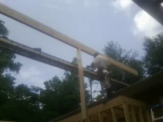 Carpenter setting a ridge beam over a new addition frame — Ice Dam Removal by Roofing Brothers in Yarmouth Port