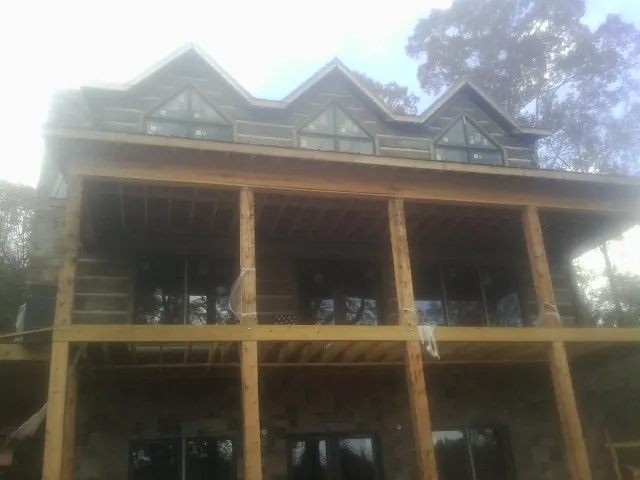 Dormers and porch framing on a large log home under construction — Roof Coating work by our crew in Yarmouth Port