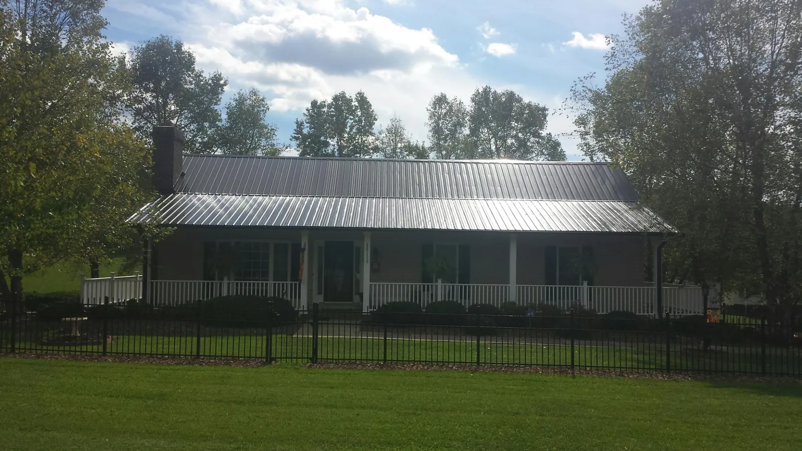 Gray metal roof on a brick ranch with a full width front porch — Gutter Guard Installation work by our crew in Yarmouth Port