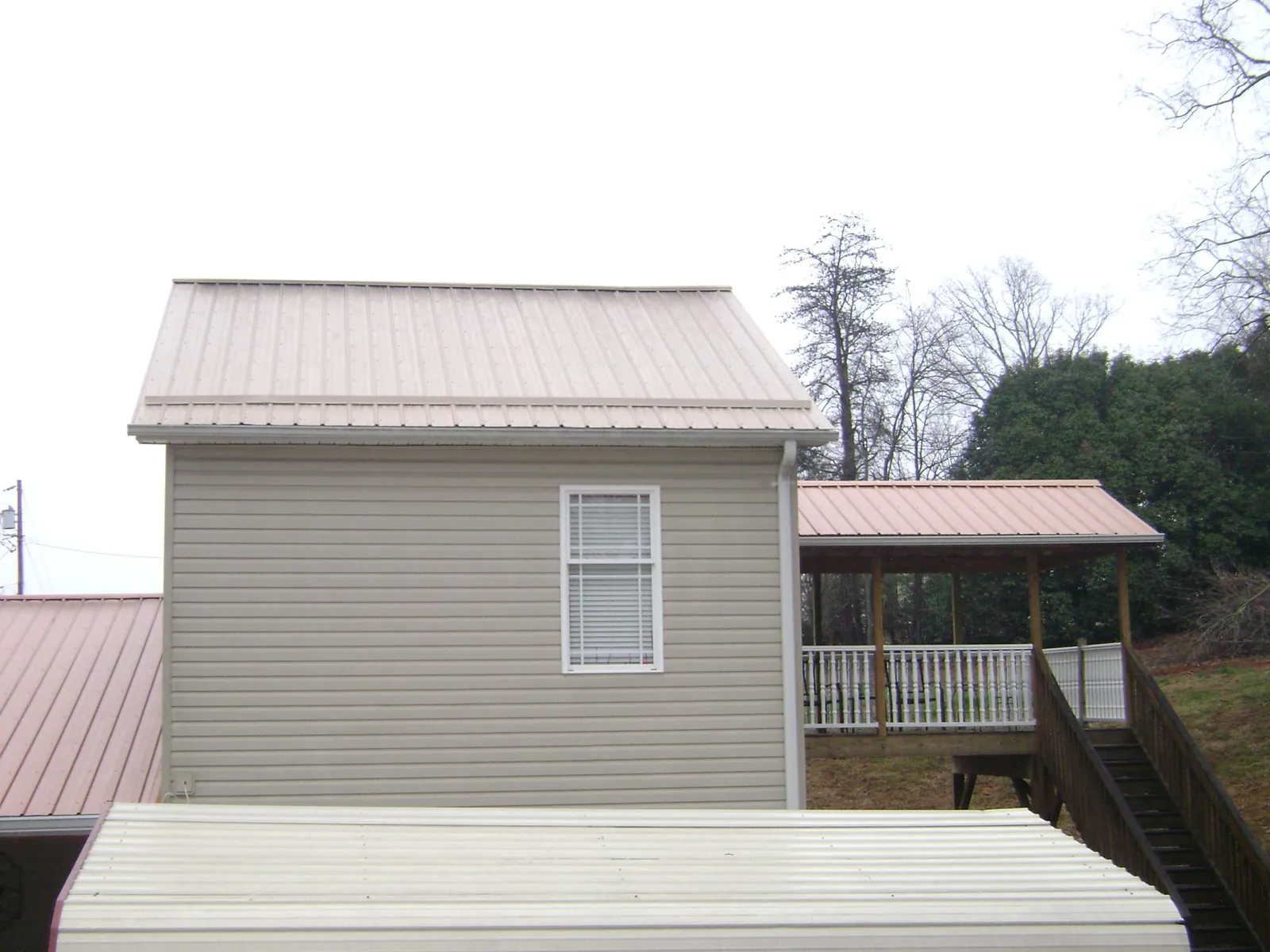 Tan metal roofs on a two story addition and attached porch, from a Roof Replacement job in Yarmouth Port