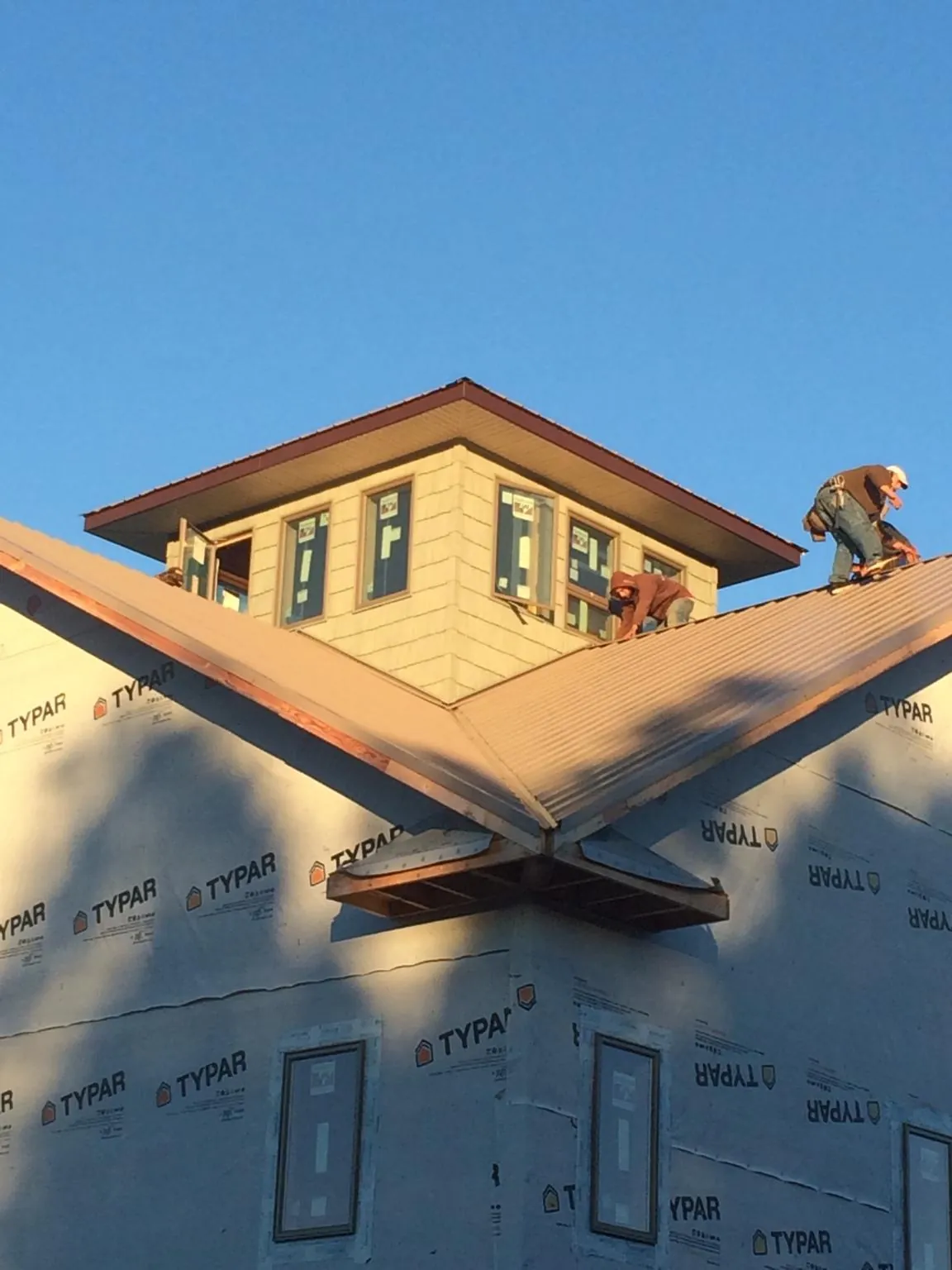 Roofers working around a rooftop cupola on a new metal roof at sunset — Roof Waterproofing in Yarmouth Port by Roofing Brothers